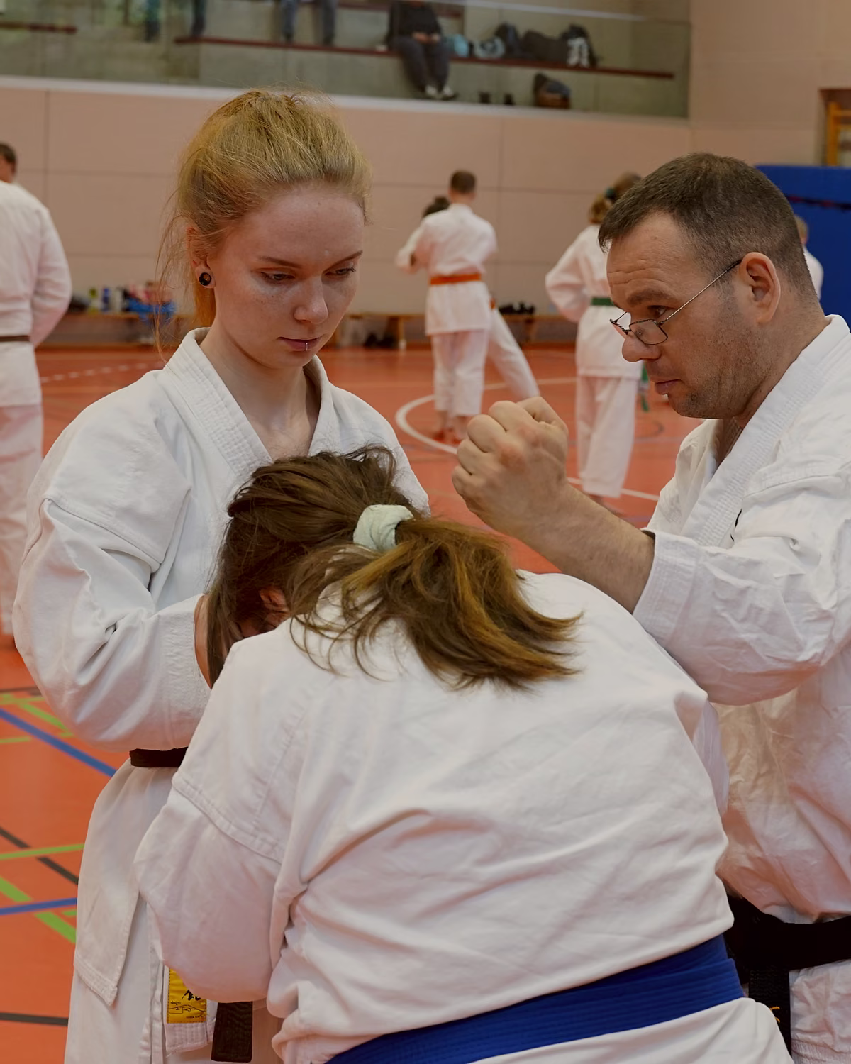 Ein Trainer korrigiert zwei Erwachsene bei einer Partner&uuml;bung