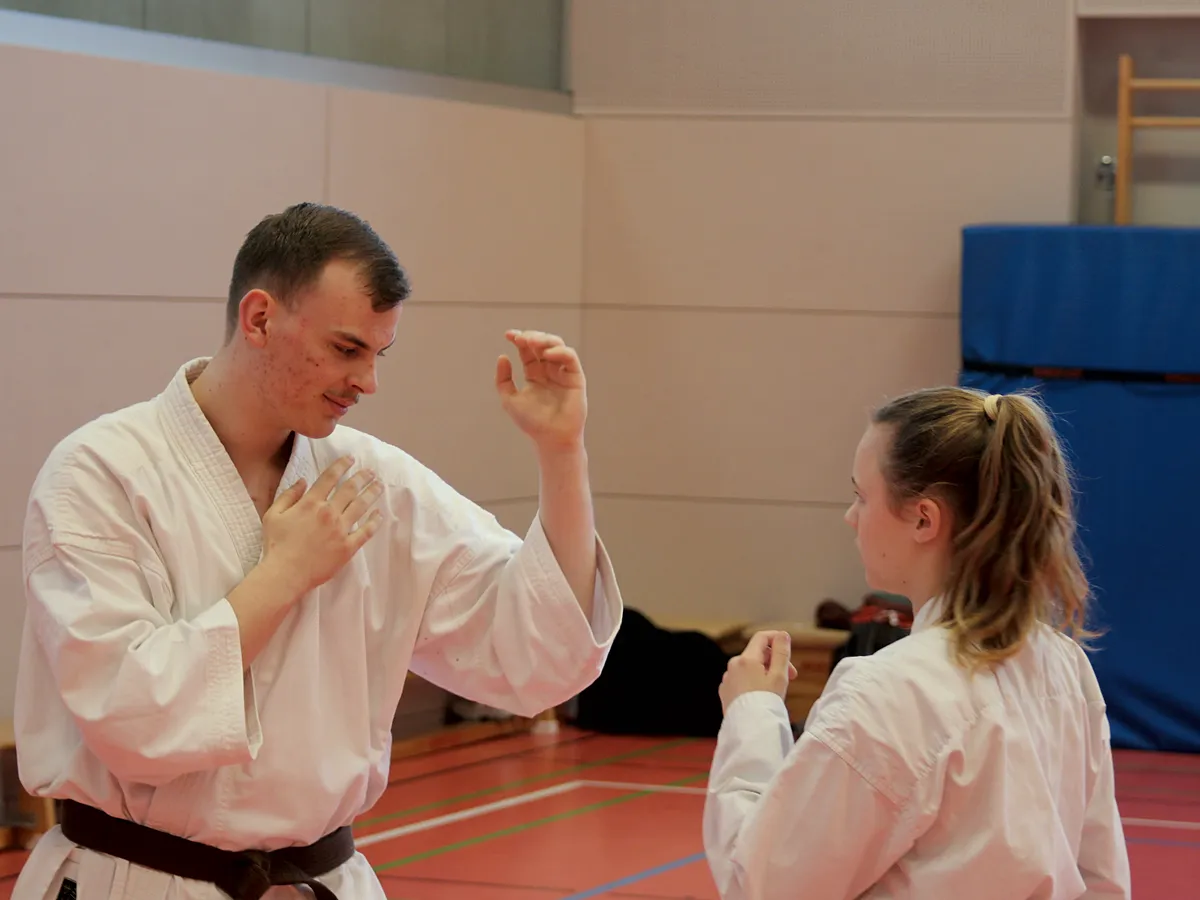 Ein Karateka zeigt mit offenen H&auml;nden eine abwehrende Haltung gegen&uuml;ber seiner Partnerin